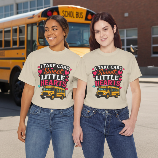 Two women wearing the I Take Care of Sweet Little Hearts tee in front of a yellow school bus